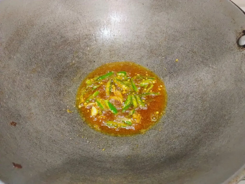 Take a pan. heat a pan on medium flame and add 3-4 teaspoons of oil. Add black mustard seeds, 5 curry leaves, add garlic paste, 3 green chilies, ¼ teaspoon turmeric powder, ¼ teaspoon red chili powder, and mix well.