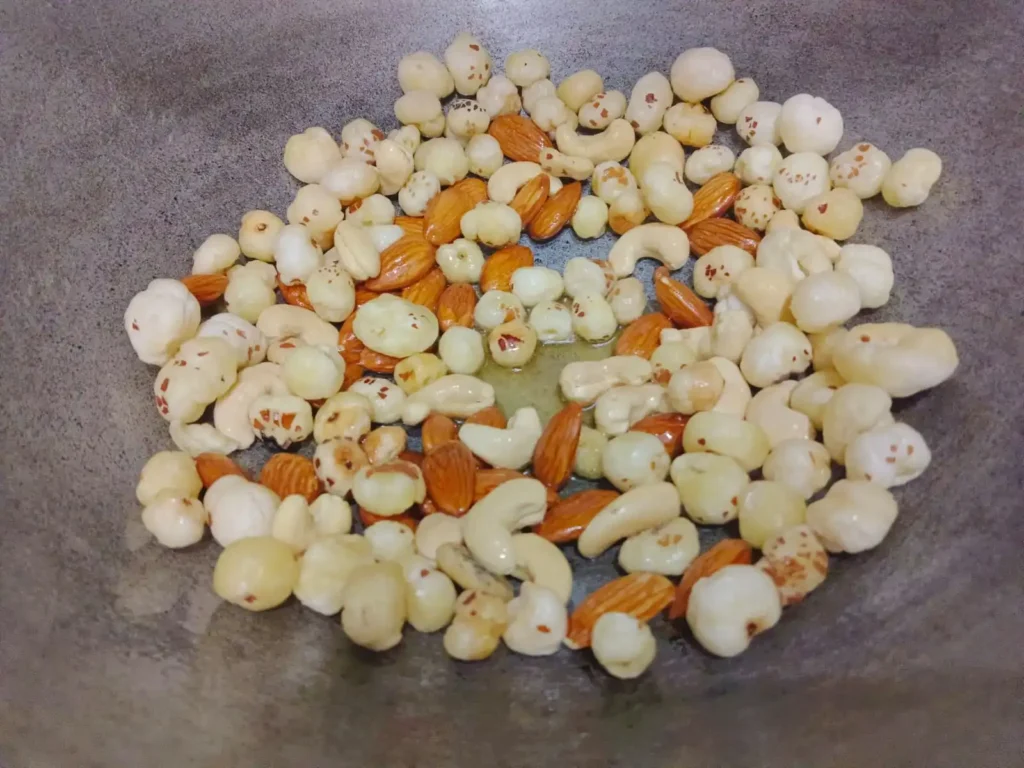 1: In a pan, heat 2-3 tsp of ghee and add almonds, cashews and makhana, frying on low-medium heat until light brown. Allow to cool and then blend to a coarse powder and place in a bowl.