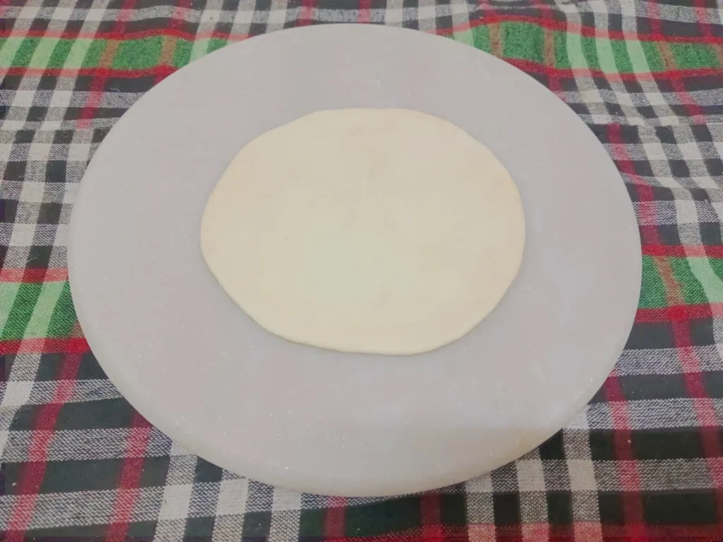 1. Take some small bits of dough and shape into little balls (like puri). Then roll out each little ball as round as possible.