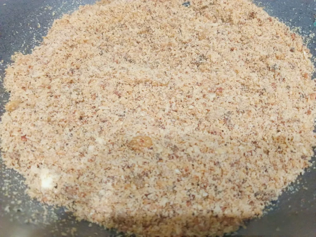 5. Now add roasted suji, ground coconut, dry fruit powder, raisins, chironji and bhura sugar; stir all together for 5-6 mins before removing heat and allowing to cool completely.