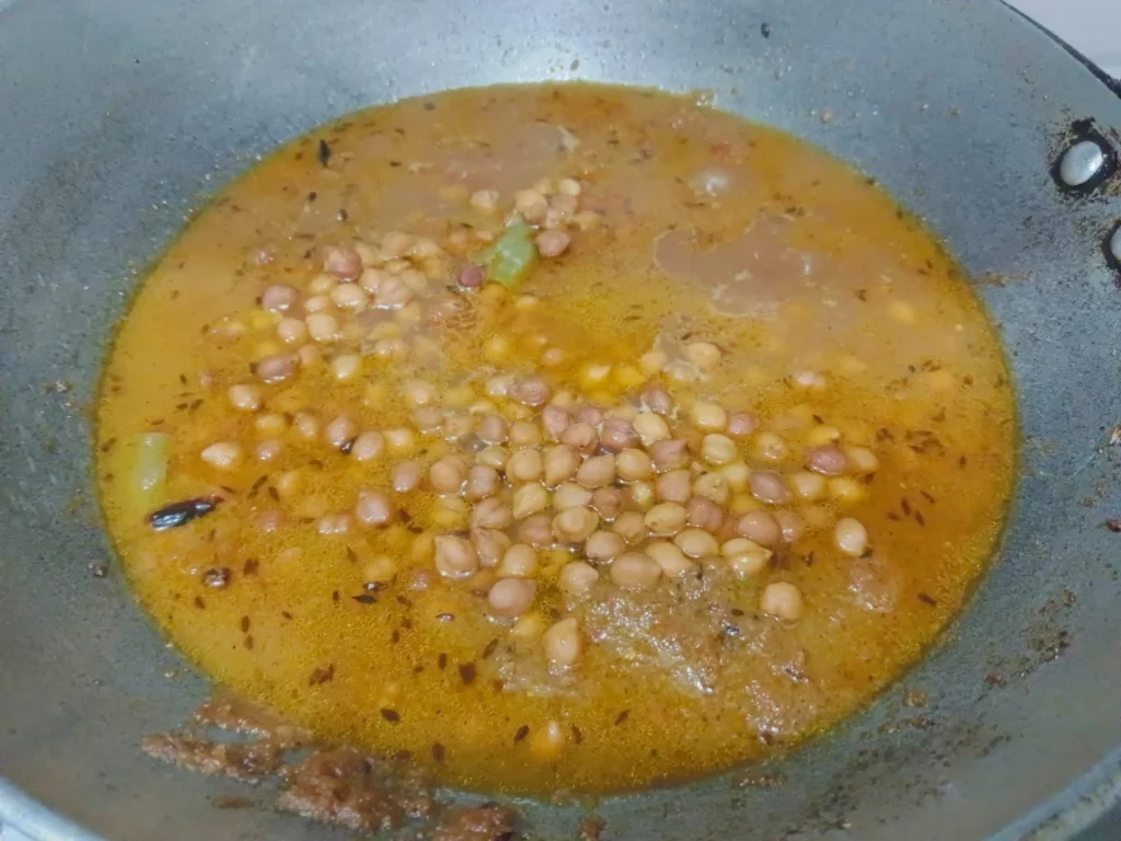 Add the boiled kala chane and mix the curry properly until the chickpeas become coated in the masala. Now add a little chana water and let the curry simmer for 2 minutes.