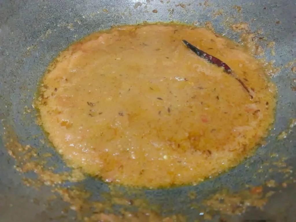 Now add the tomato & green chilli paste and salt and sauté the mixture until the curry becomes thick and tasty.